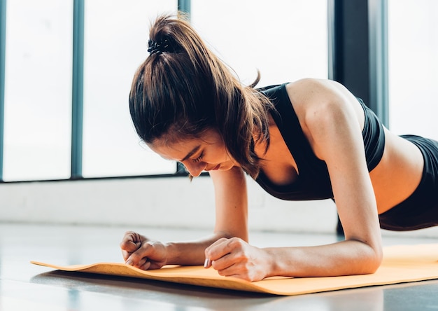 Beautiful woman exercise workout with planking on mat at fitness GYM