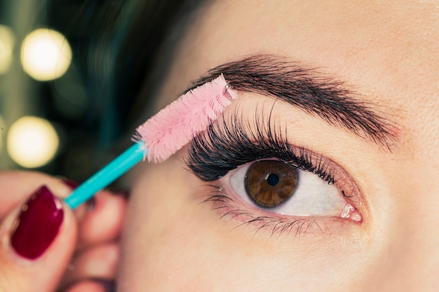 beautiful woman eyes make-up. mascara applying. long lashes closeup. mascara brush. eyelashes extensions. makeup for black eyes. eye make up apply, eyebrows shaping.