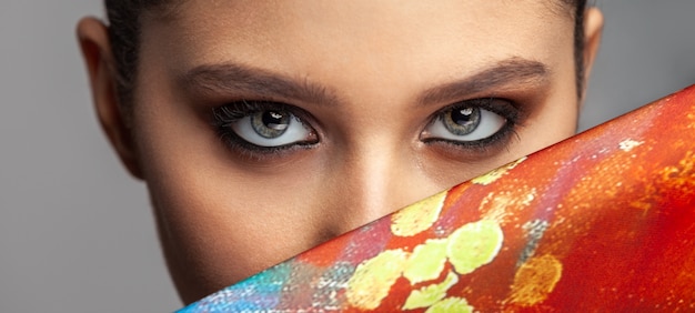 Photo beautiful woman eyes and makeup next to a colored silk cloth