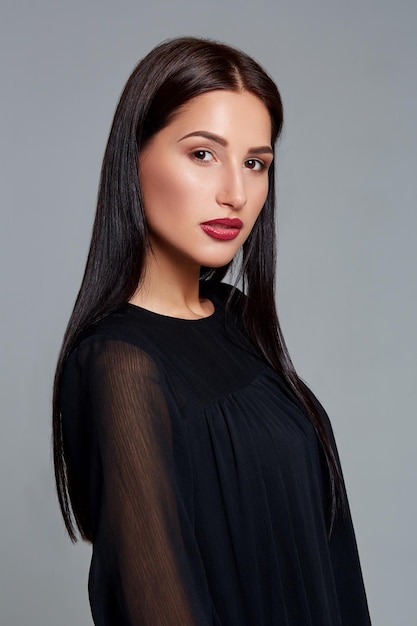 Beautiful woman face close up portrait young studio on gray. Woman in black dress