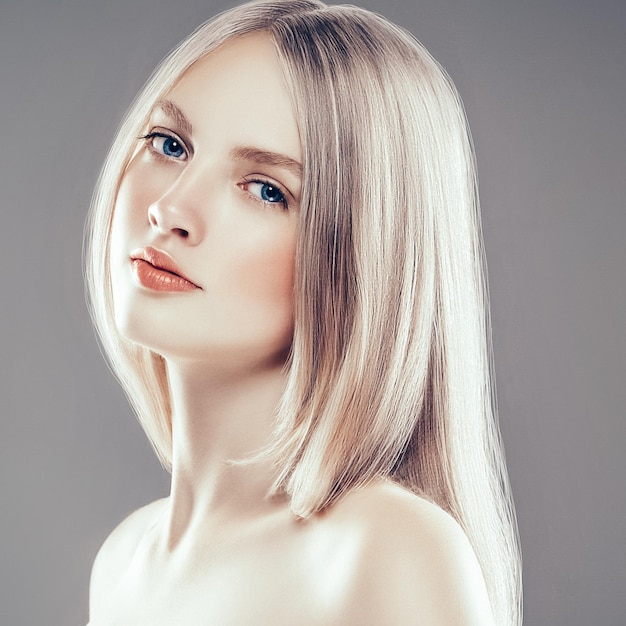 Beautiful Woman Face Portrait Beauty Skin Care Concept with long blonde hair. Fashion Beauty Model with beautiful hairstyle over gray background