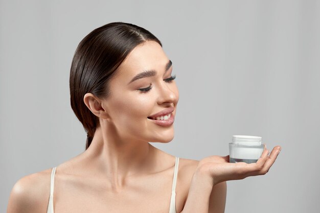 Photo beautiful woman face skin care portrait of attractive young female applying cosmetics cream