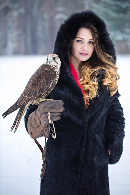 Beautiful woman and falcon in winter