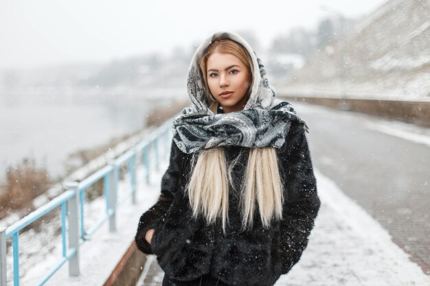 Beautiful woman in fashion stylish scarf in winter snowy day