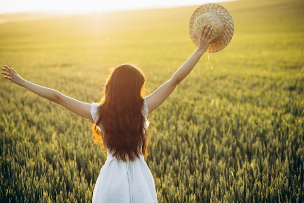 Beautiful woman in the field wearing white dress and hat