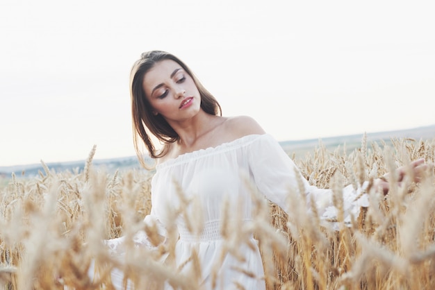 Beautiful woman in a field of wheat in a white dress, a perfect picture in the style lifestyle