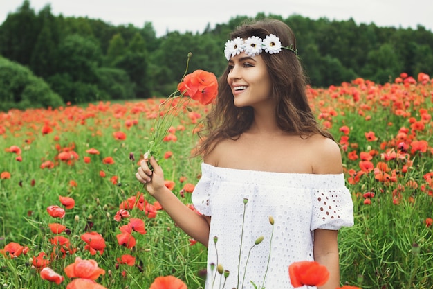 Beautiful woman in field with a lot of poppy flowers