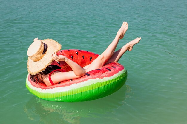 青い湖の水のインフレータブルリングに浮かぶ美しい女性夏の晴れた日