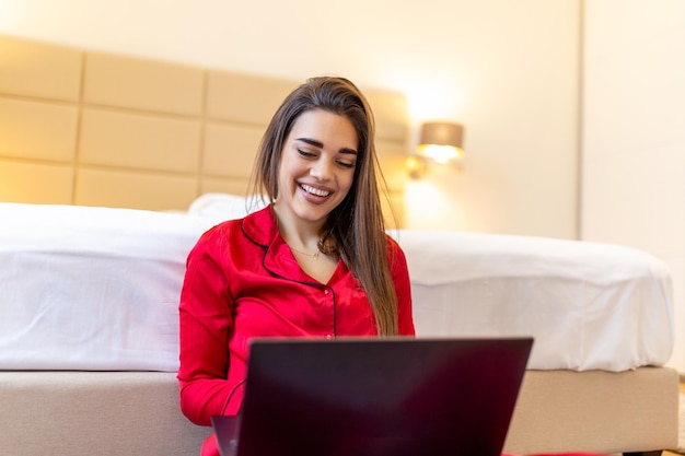 Beautiful woman freelancer noting information for planning project doing remote job via laptop computer laughing while reading email on modern laptop device