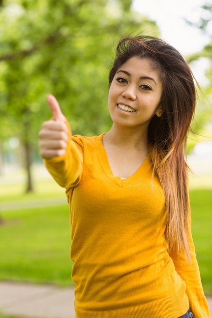 Beautiful woman gesturing thumbs up in park