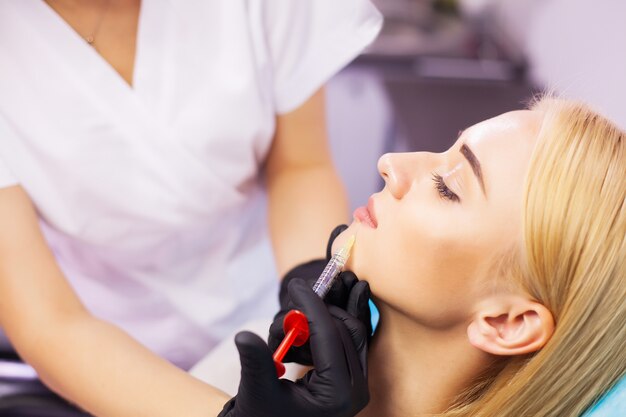 Beautiful woman getting beauty injection for lips