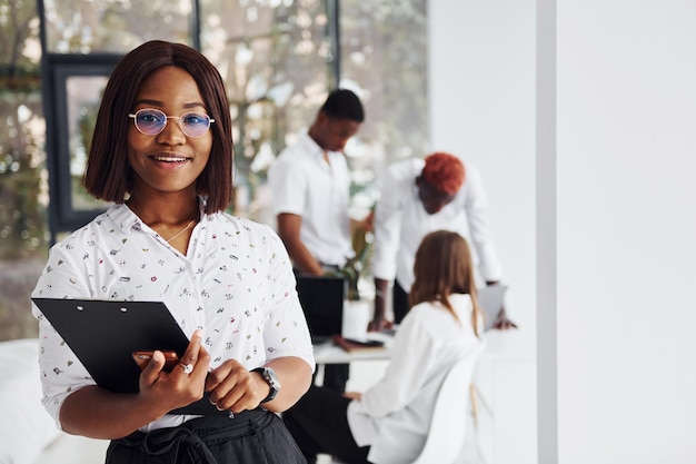 Beautiful woman in glasses in front of her colleagues Group of african american business people working in office together
