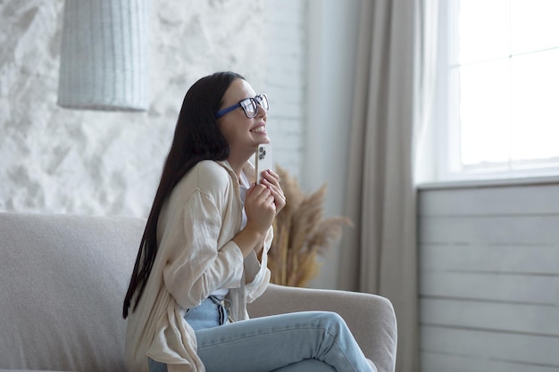 A beautiful woman in glasses is happy she received good news online message she is delighted sitting