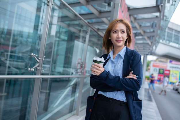 Beautiful Woman Going To Work With Coffee Walking Near Office Building Portrait Of Successful Business Woman Holding Cup Of Hot Drink In Hand On Her Way To Work On City Street High Resolution