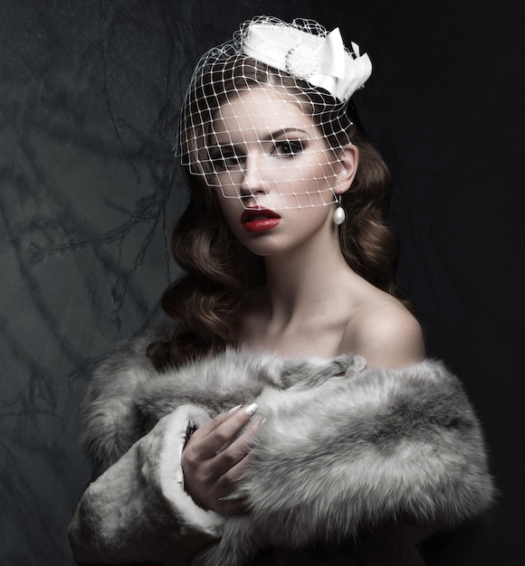 Beautiful woman in gothic style with evening makeup and red nails with thorns. Picture taken in a studio on a red background.