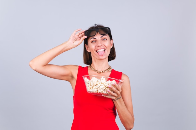 Beautiful woman on gray wall in 3d cinema glasses with popcorn, cheerful happy positive emotions