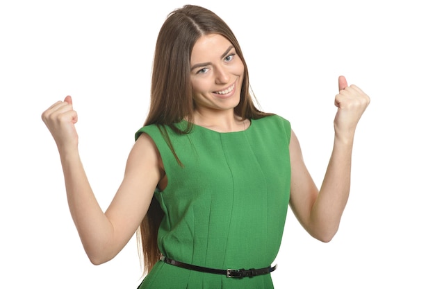 Foto bella donna in vestito verde che gesturing il segno del vincitore su priorità bassa bianca