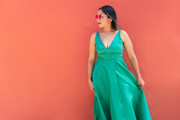 通りの緑のドレスとサングラスの美しい女性