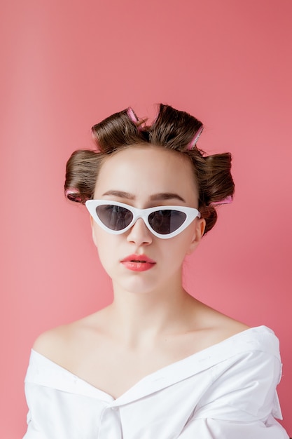 Beautiful woman in hair curlers on pink