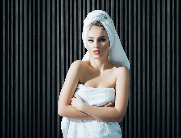 入浴後の美しい女性のハンドルタオルカメラを見て彼女の頭にタオルを巻いた半裸の女性の美しさの肖像画