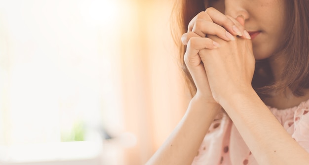 Belle mani della donna che pregano al dio.