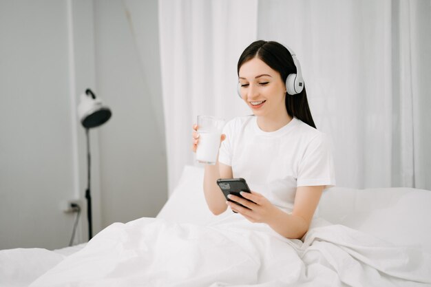 Photo beautiful woman has woken up on a white bed and holding coffee in the morning at home in morning lifestyle concept