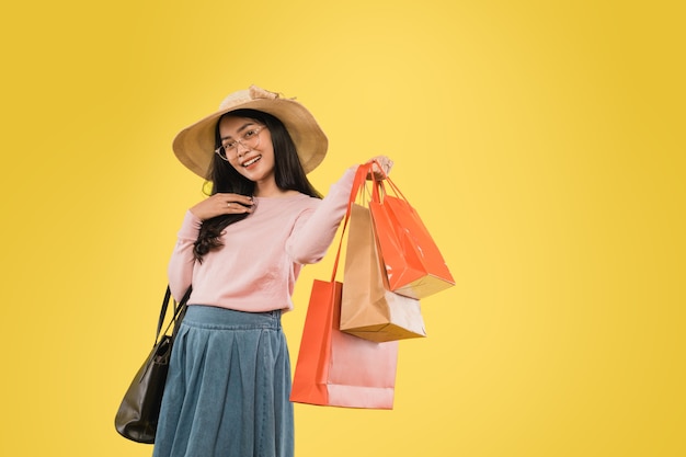 ショッピングの紙袋を運ぶ手で笑って帽子とメガネの美しい女性