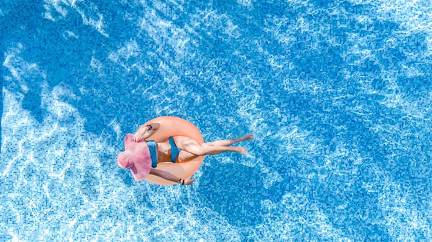 Beautiful woman in hat in swimming pool aerial drone view from above young girl in bikini relaxes