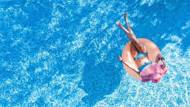 Beautiful woman in hat in swimming pool aerial top view from above young girl in bikini relaxes