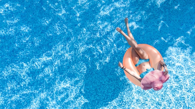 Bella donna con cappello in piscina vista dall'alto aerea dall'alto giovane ragazza in bikini si rilassa