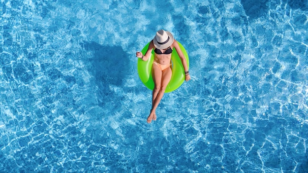 Beautiful woman in hat in swimming pool aerial top view from above, young girl in bikini relaxes