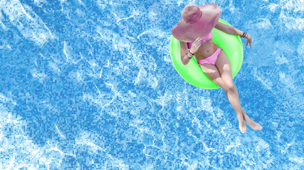 Beautiful woman in hat in swimming pool aerial top view from above