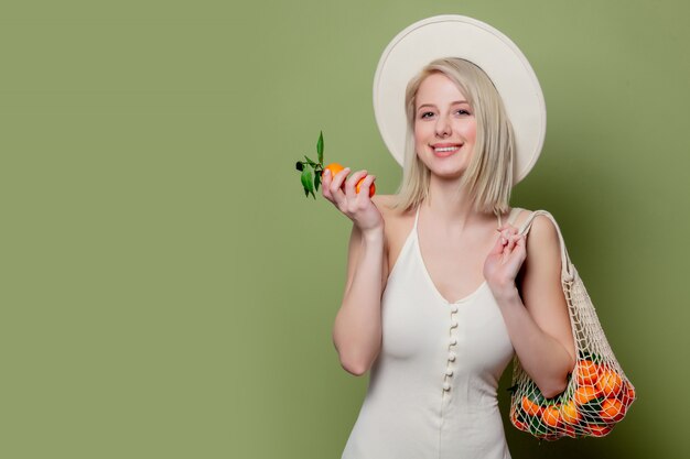 Beautiful woman in a hat and white dress with a mandarins