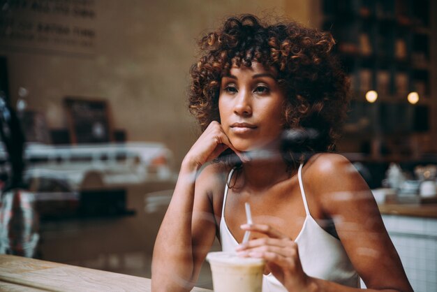 Beautiful woman having a drink inside a cafe, view through the screen