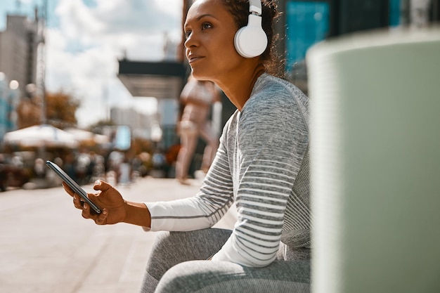 Foto bella donna in cuffia che ascolta la musica mentre si riposa dopo l'allenamento