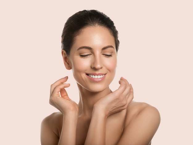 Beautiful woman healthy skin beauty face cosmetic concept touching her face color background. Pink