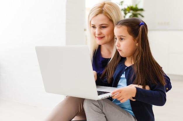 Beautiful woman helping her daughter doing her homework in a kitchen