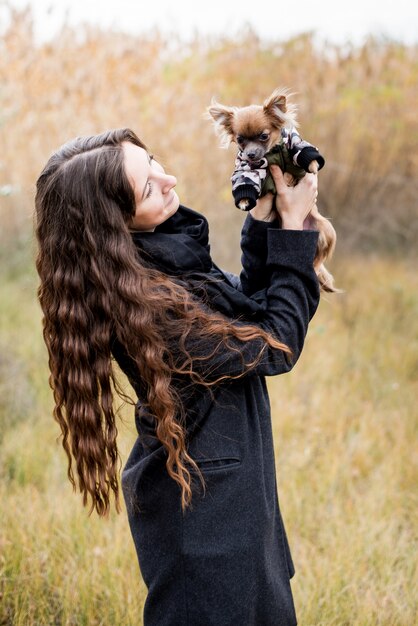 Beautiful woman and her dog chihuahua in cloth in the autumn park