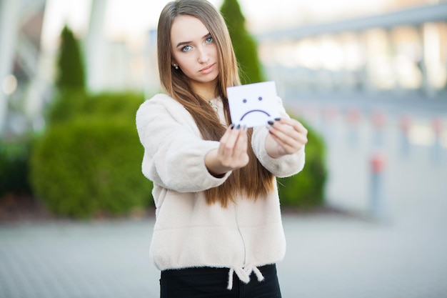 Beautiful woman holding card with sad smile
