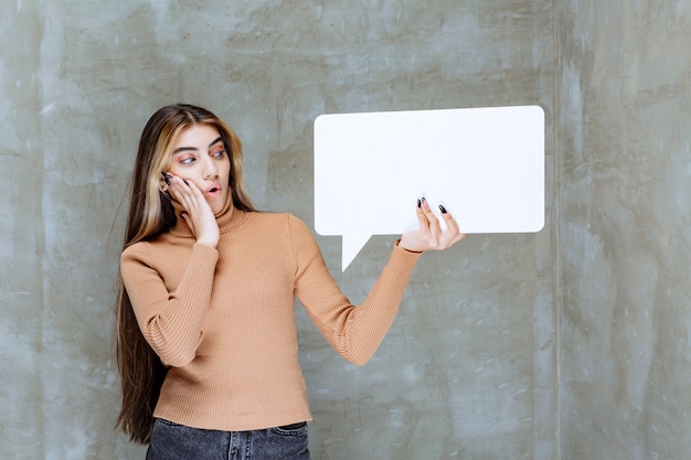 Beautiful woman holding empty speech bubble on a stone 