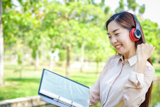 Beautiful woman holding a file and wearing headphones She is happy to work.