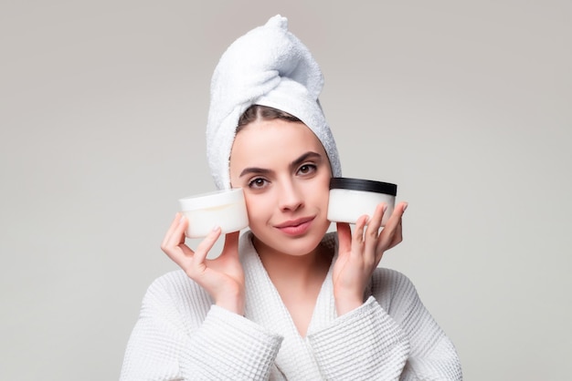 Beautiful woman holding jar of cream portrait of beauty girl putting cosmetic cream on face female s