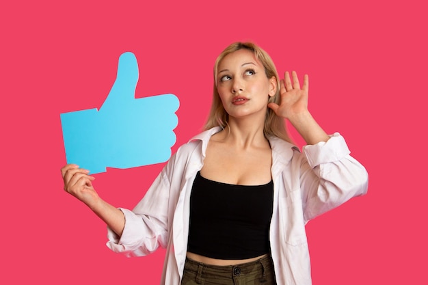 Photo beautiful woman holding a like button isolated on pink background