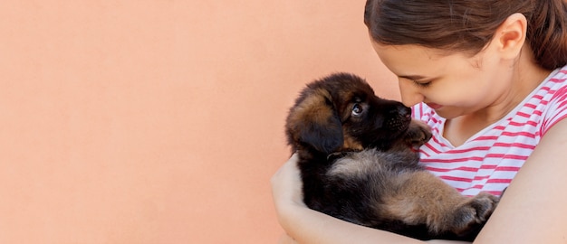 Beautiful woman holding and looking into black puppy's eyes