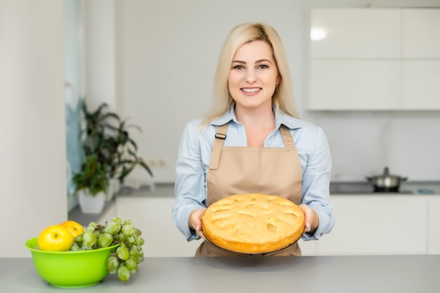 Beautiful woman holding pie in the kitchen