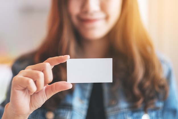 A beautiful woman holding and showing a blank empty business card to someone