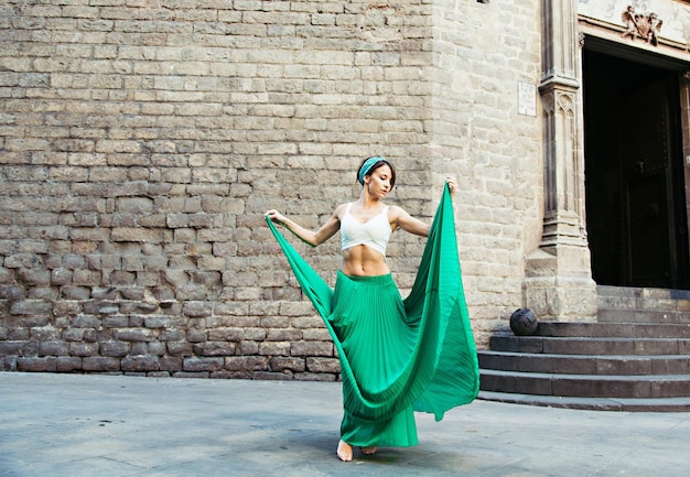 beautiful woman holding skirt while standing on street against building