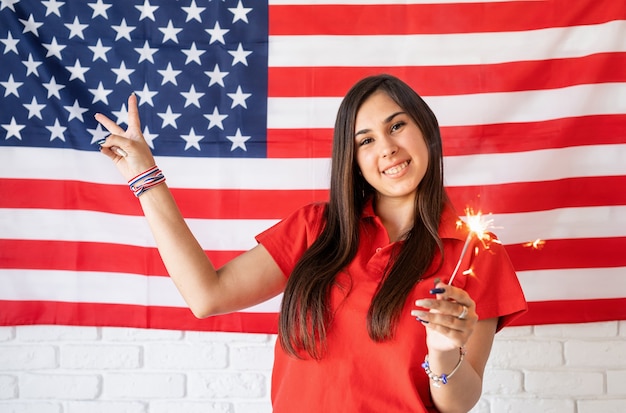 Beautiful woman holding a sparkler on the US flag background