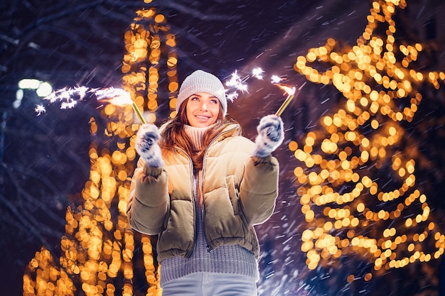 Beautiful woman holding sparkles and have fun in the open air