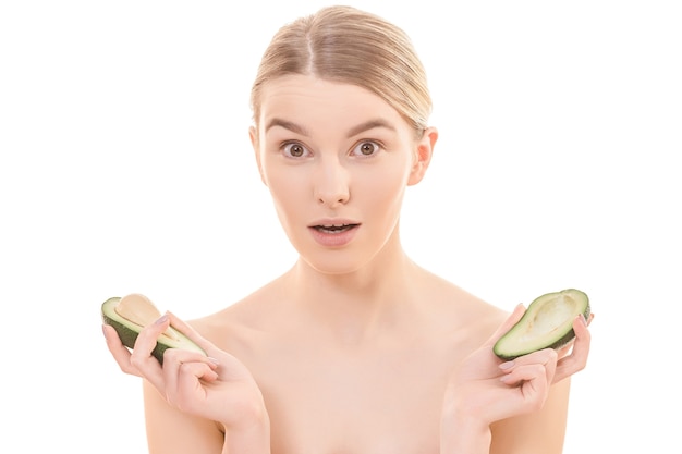 The beautiful woman holding two halves of a avocado on the white background